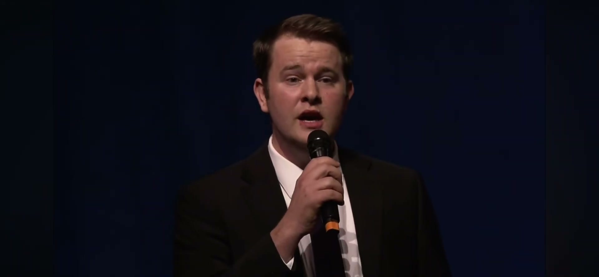 Royal Grubbs singing into a handheld microphone on stage